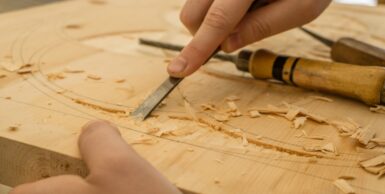 person using chisel while curving wood